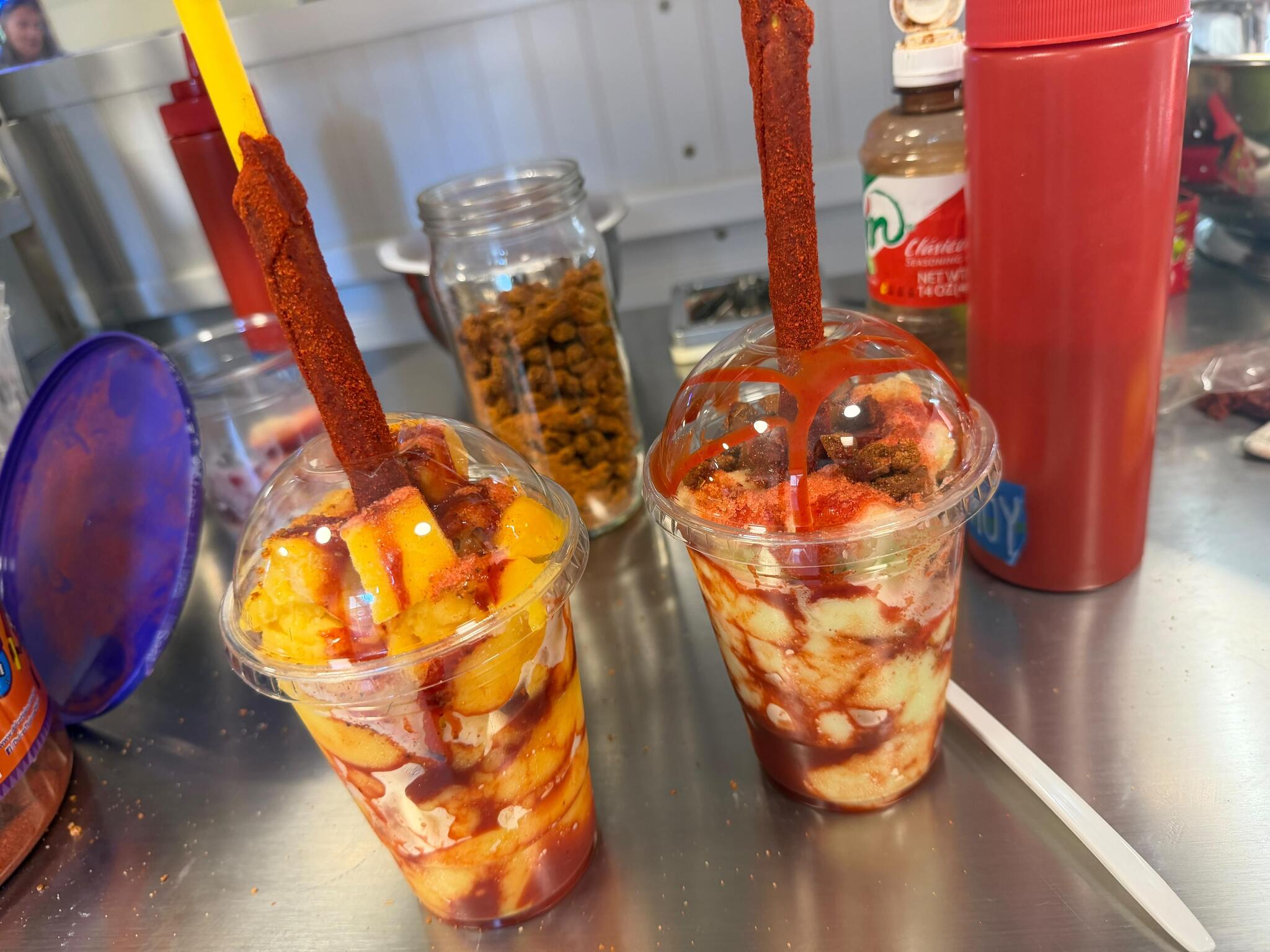 Two chamoy and Tajín mango cups with tamarindo candy straws
